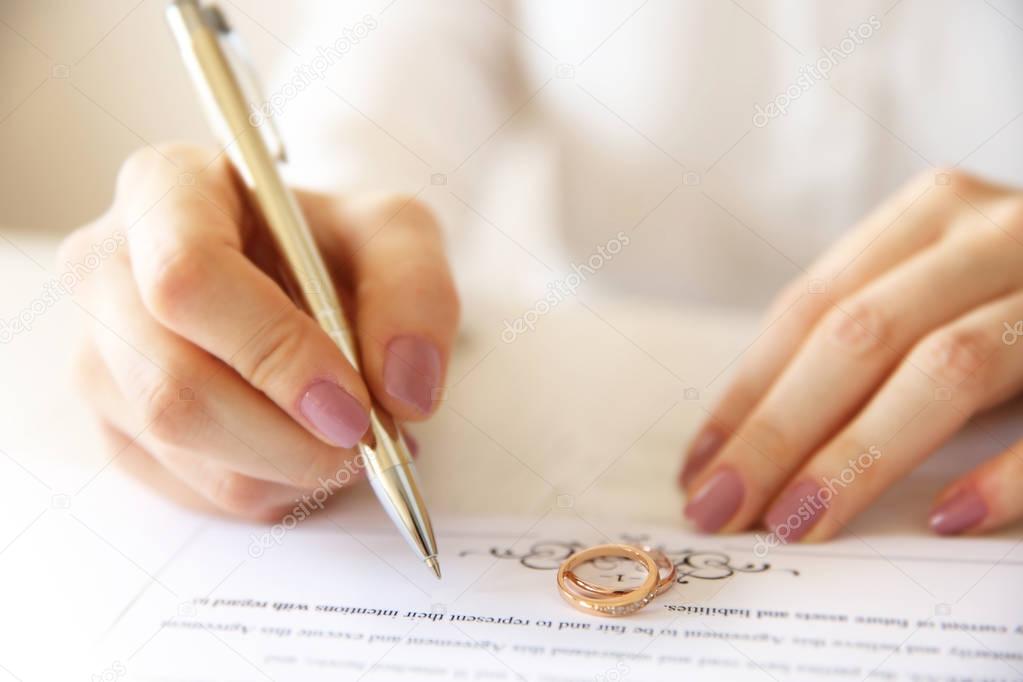 Woman signing marriage contract, closeup