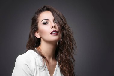 Güzel genç kadın modeli koyu arka plan üzerinde parlak makyaj ile portresi