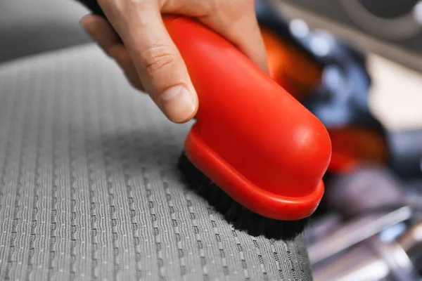 Male hand cleaning car with brush inside — Stock Photo, Image