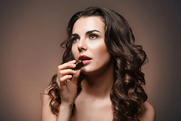 Beautiful girl with chocolate on brown background — Stock Photo, Image