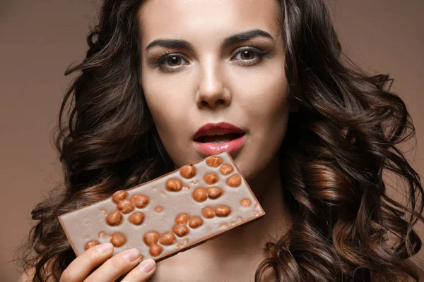 Mooi meisje met chocolade op bruine achtergrond — Stockfoto