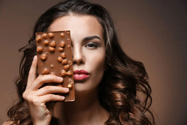 Mooi meisje met chocolade op bruine achtergrond — Stockfoto
