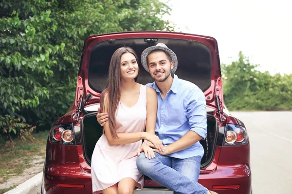 Vackra unga paret sitter i bilen stammen — Stockfoto