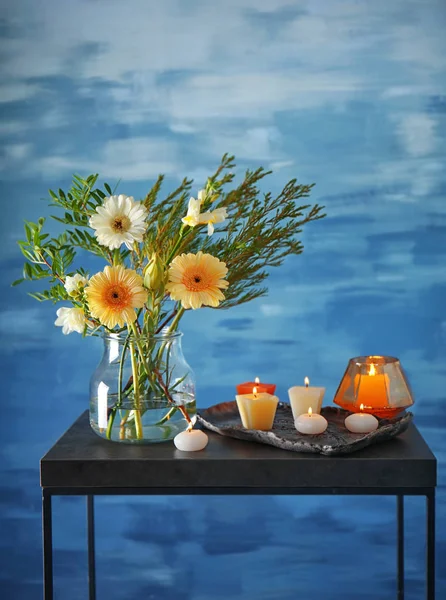 Bellissimi fiori in vaso con candele su sfondo blu — Foto Stock