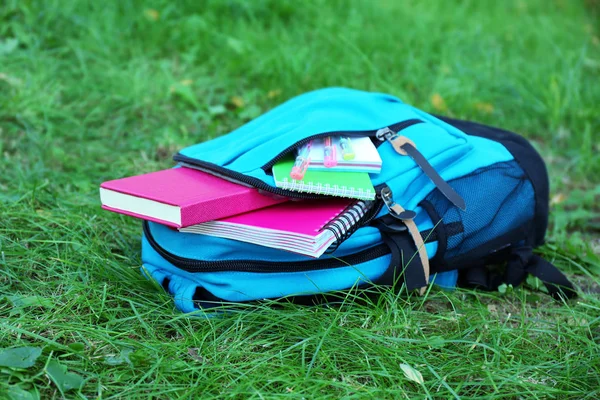 Mochila escolar con accesorios en hierba verde —  Fotos de Stock