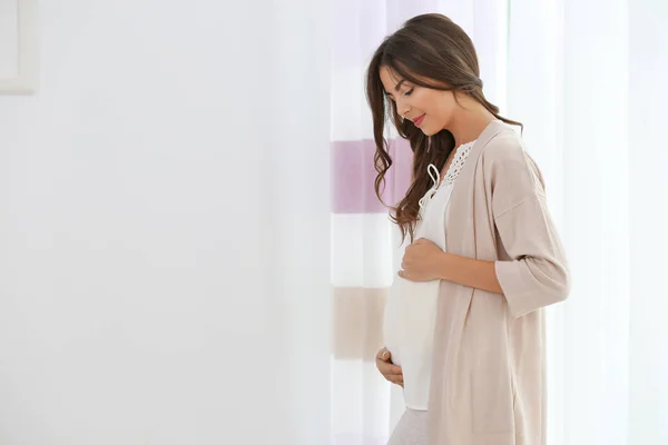 Wanita hamil berdiri di dekat jendela — Stok Foto