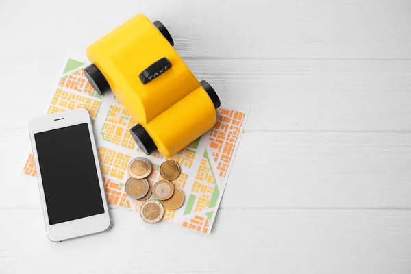 Táxi brinquedo amarelo e smartphone — Fotografia de Stock