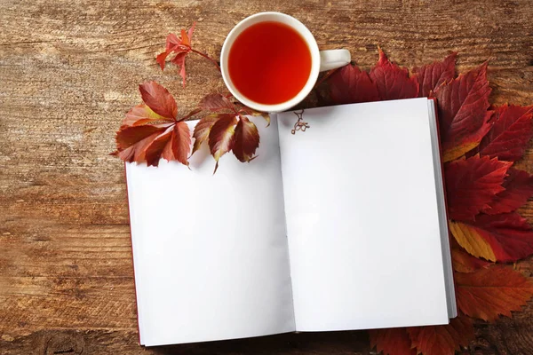 Composição de outono com livro aberto e xícara de chá em fundo de madeira — Fotografia de Stock