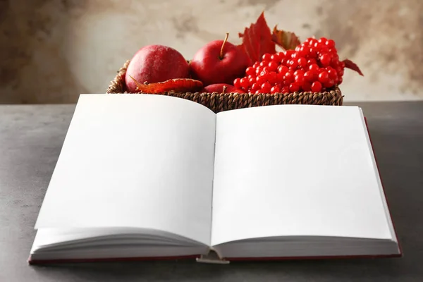 Öppnade boken och korg med höstens äpplen på grå bord — Stockfoto