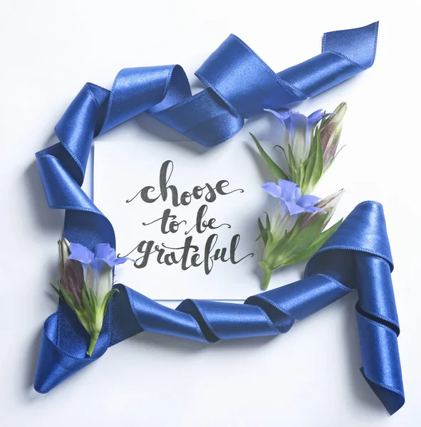 Επιγραφή «Επιλέγουν να είναι ευγνώμων» γραμμένο σε χαρτί με άνθη και κορδέλα σε άσπρο φόντο — Φωτογραφία Αρχείου