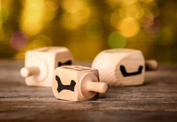 Dreidels für Chanukka auf Holztisch gegen defokussiertes Licht — Stockfoto