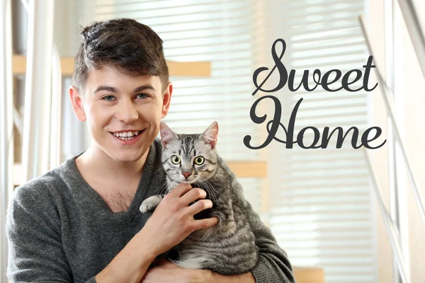 Young man with cute cat. Text SWEET HOME. — Stock Photo, Image