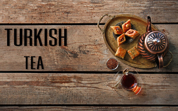 Турецкий чай в традиционном стакане со сладостями на деревянном фоне
