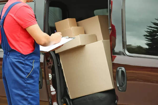 Postbote überprüft Bestellungen in der Nähe des Autos — Stockfoto