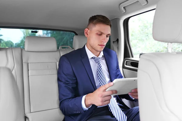 Joven hombre de negocios con tableta sentado en el coche — Foto de Stock