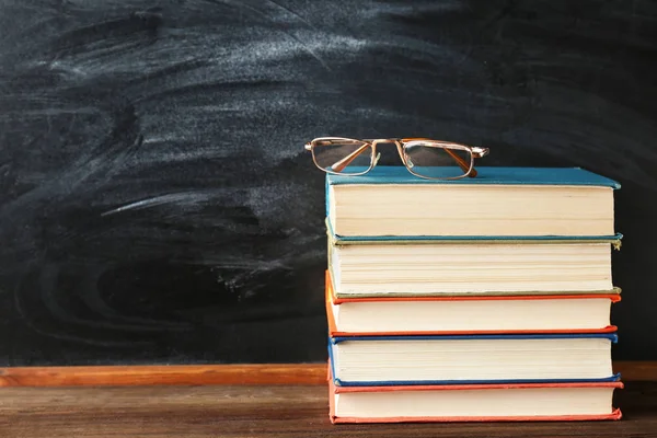 Staplade böcker, Glasögon och blackboard — Stockfoto