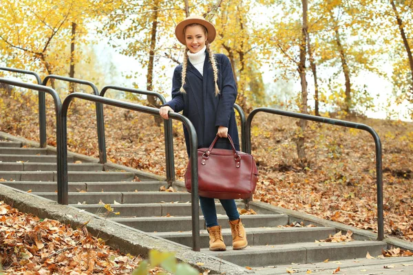 Mooi meisje met leerzak in herfst park — Stockfoto