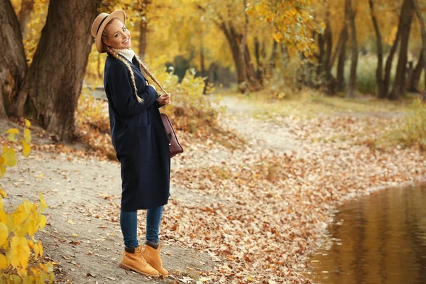 Красивая девушка с кожаной сумкой в осеннем парке — стоковое фото