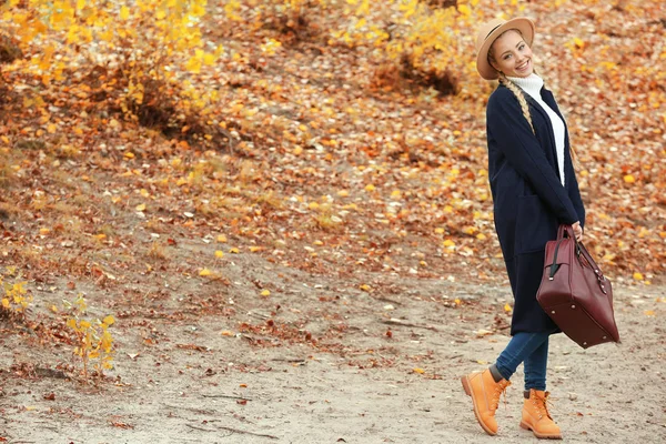 Krásná dívka s kožené pouzdro na podzim park — Stock fotografie