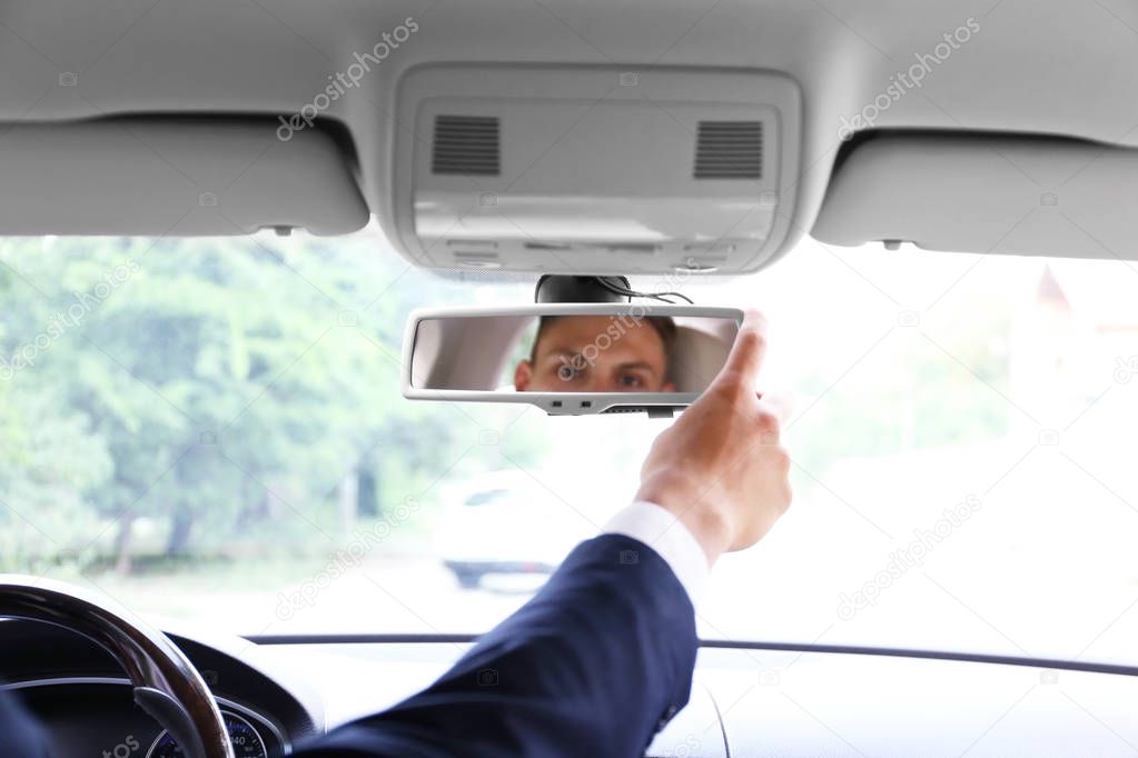 Man fixing front mirror in car