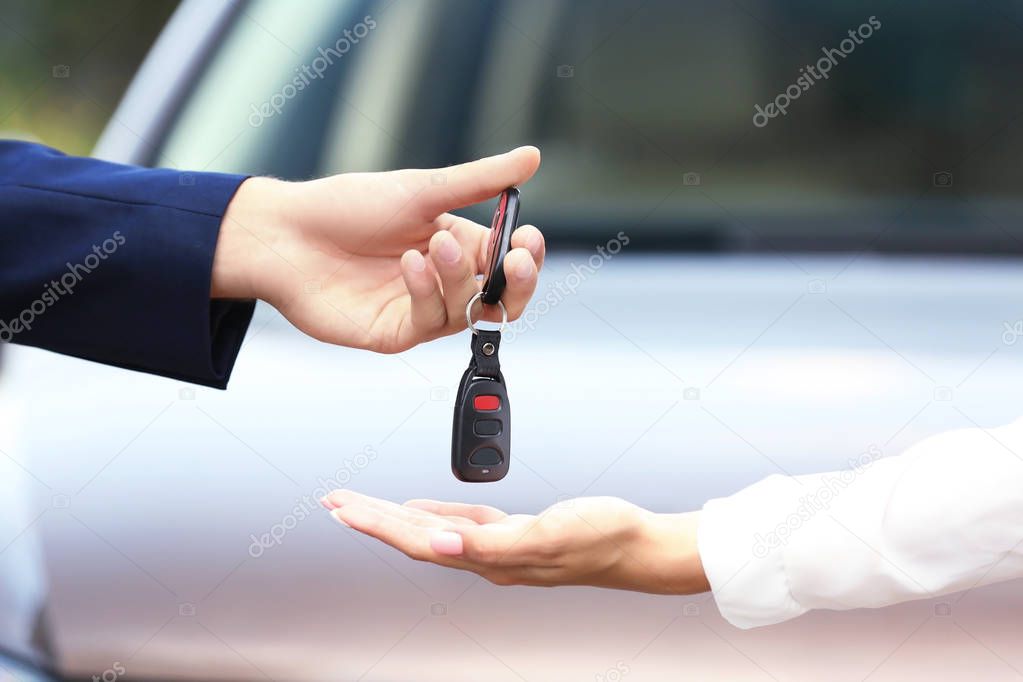 Businessman giving keys of car to woman 