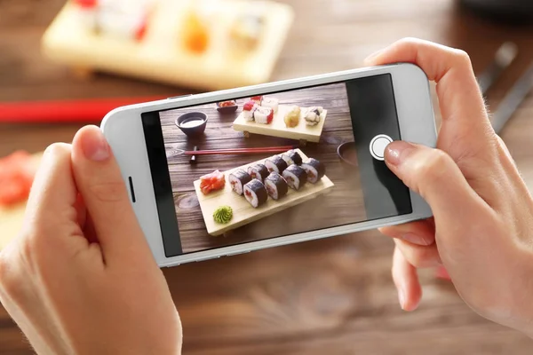 Woman taking photo of tasty sushi set — Stock Photo, Image