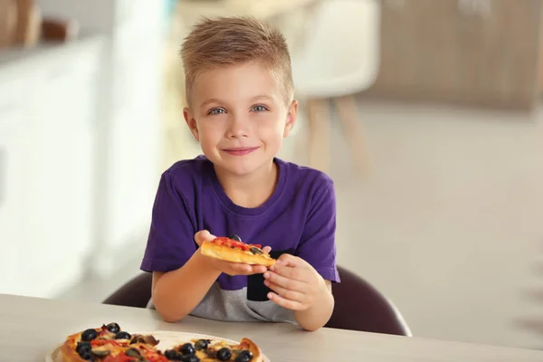 Милый мальчик ест пиццу дома — стоковое фото