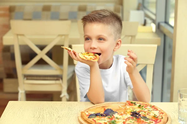 Ładny chłopak jedzenie pizza w restauracji — Zdjęcie stockowe