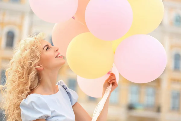Hermosa mujer joven sosteniendo globos de aire en la calle — Foto de Stock