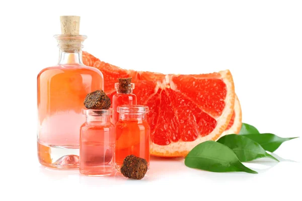 Grapefruit, leaves and bottles with essential oil on white background — Stock Photo, Image