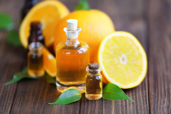 Orange, leaves and bottles with essential oil on wooden table — Stock Photo, Image