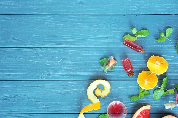 Toranja, laranja, casca, hortelã e garrafas com óleo essencial sobre mesa de madeira, vista superior — Fotografia de Stock