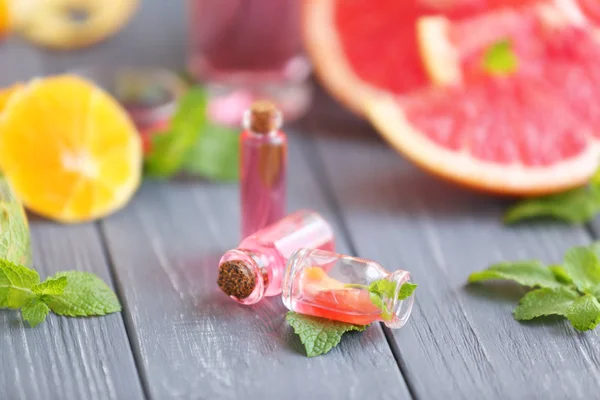 Flaschen ätherisches Öl und Minzblätter auf Holztisch — Stockfoto