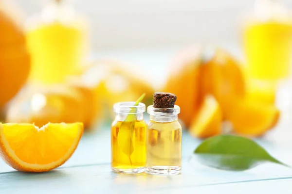 Zwei Flaschen mit ätherischem Öl, Orangenscheibe und Blatt auf Holztisch — Stockfoto