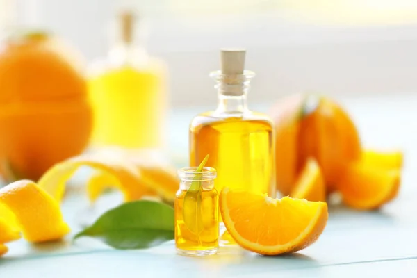 Two bottles with essential oil, orange slice, peel and leaf on wooden table — Stock Photo, Image