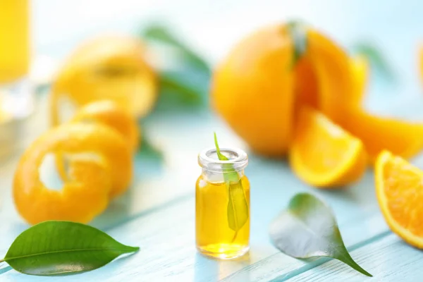 Bottle with essential oil, orange slice and leaves on wooden table — Stock Photo, Image