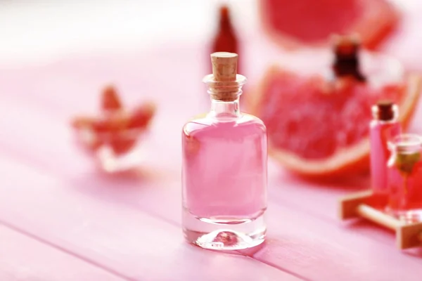ピンクの木製テーブルのエッセンシャル オイルのボトル — ストック写真