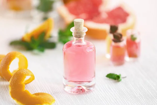 Bottle with essential oil and orange peel on wooden table — Stock Photo, Image