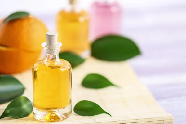 Bottle with essential oil and leaves on bamboo napkin — Stock Photo, Image