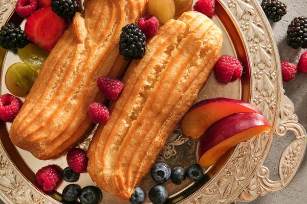 Tasty eclairs and fruits on tray, closeup — Stock Photo, Image