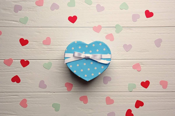 Подарочная коробка в форме сердца с маленькими сердцами на деревянном столе — стоковое фото