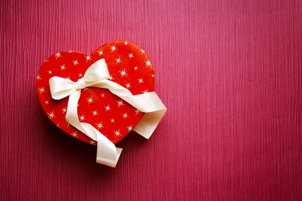 Herzförmige Geschenkschachtel auf lila strukturiertem Hintergrund — Stockfoto