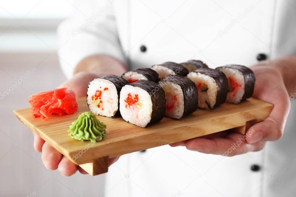 Sushi master holding wooden board with delicious sushi set