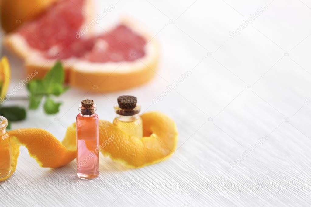 Bottles with essential oil and orange peel on wooden table