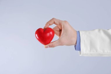 Işık arka plan üzerinde kırmızı kalp tutan erkek doktor el görünümü kapatın