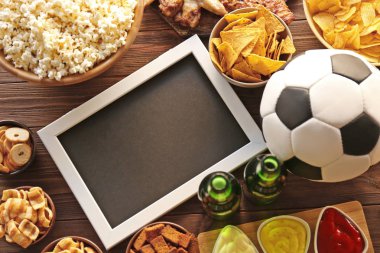 Ball, frame, beer and tasty snacks on wooden table clipart