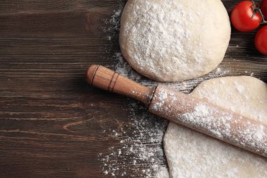 Çiğ pizza hamuru ve ahşap masa malzemeleri.