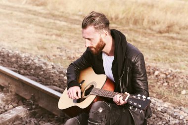 Yakışıklı adam demiryolu üzerinde gitar çalmak