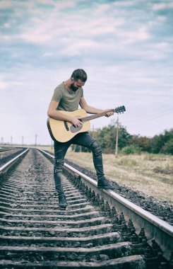 Yakışıklı adam demiryolu üzerinde gitar çalmak