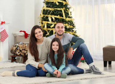 Aile halı oturma odasında oturup Noel için dekore edilmiş